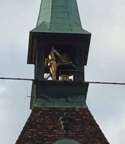 The bronze man at the top striking the bell with his hammer.